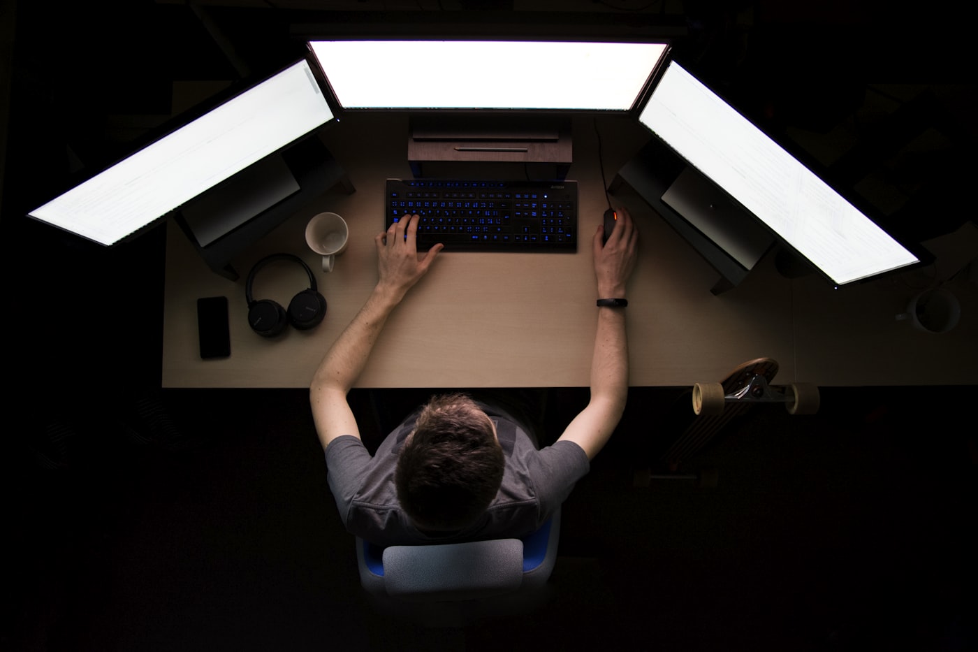 Engineer working across three monitors in a dark studio